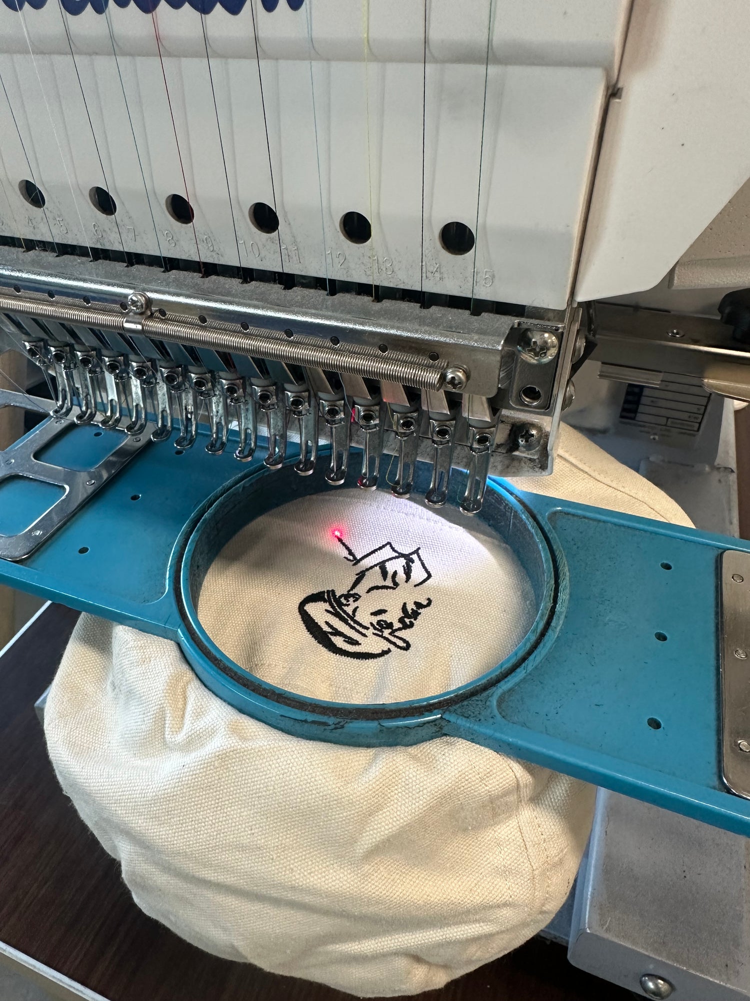 Machine à broder le logo Le Style En Tête sur une casquette, illustrant l'engagement pour l'artisanat local et les finitions en France.